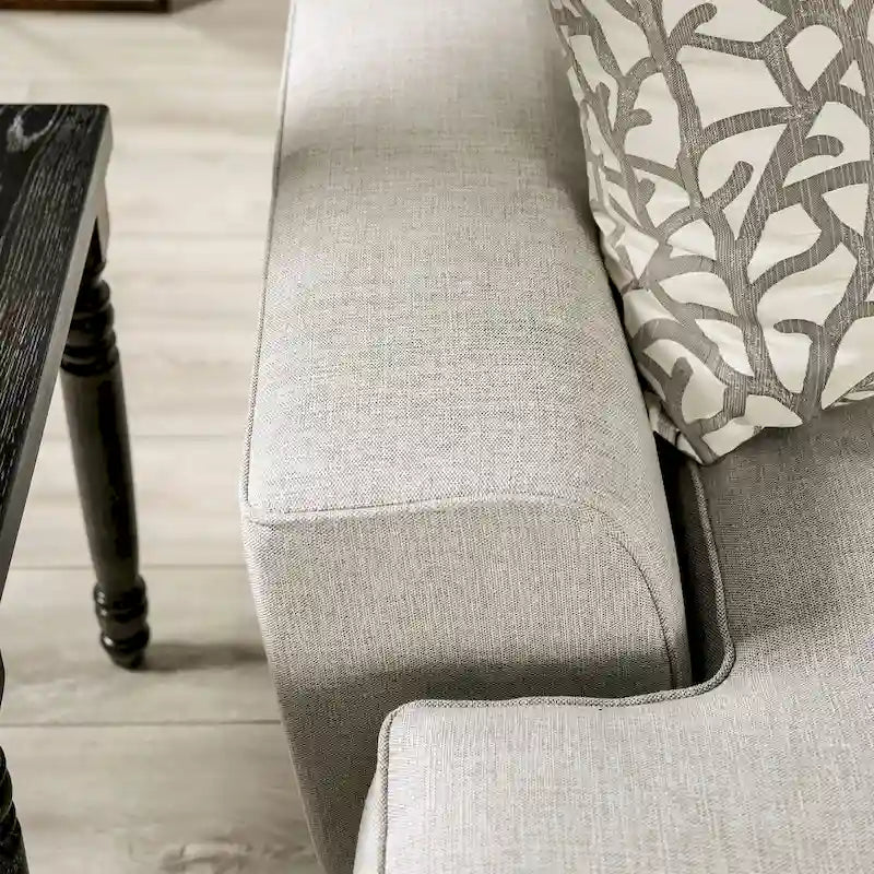 A light gray fabric upholstered sofa with a blue-toned transition style, adorned with rivets and featuring cushions.