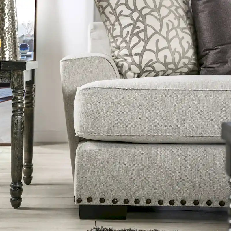 A light gray fabric upholstered sofa with a blue-toned transition style, adorned with rivets and featuring cushions.