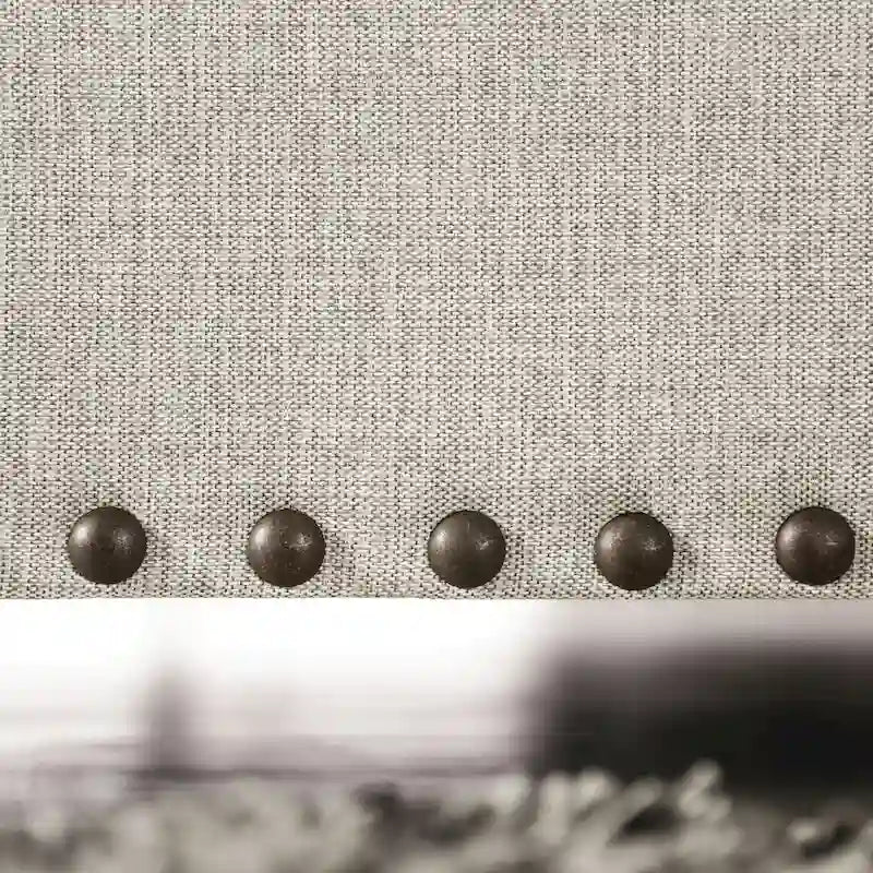 A light gray fabric upholstered sofa with a blue-toned transition style, adorned with rivets and featuring cushions.