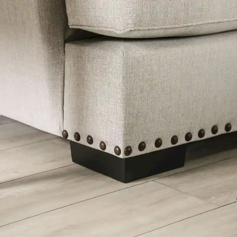 A light gray fabric upholstered sofa with a blue-toned transition style, adorned with rivets and featuring cushions.
